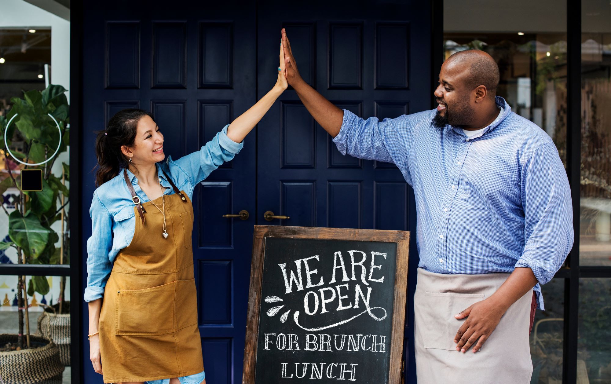 Business owners high fiving each other standing near their store