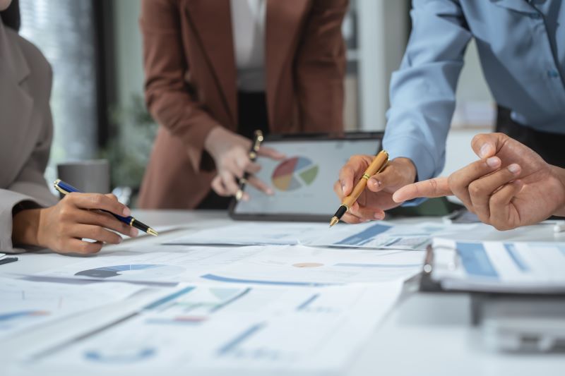 Entrepreneurs, marketers, managers, and financial analysts gather around the table to analyze data